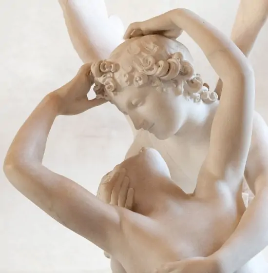 Détail de la sculpture en marbre blanc de Cupidon et Psyché s'embrassant. Cupidon se penche vers Psyché dont la tête est inclinée.