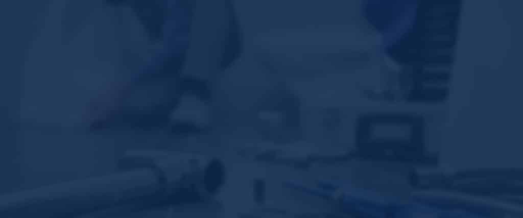 Gros plan flou sur un plan de travail sombre avec des outils métalliques et un tournevis bleu, ambiance technique bleue.